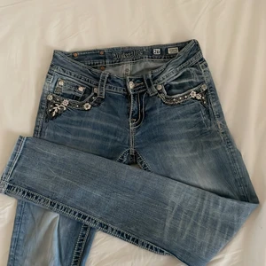 Y2k miss me jeans - Snygga y2k miss me jeans. Passformen är skinny lowwaist i storlek 26, mindjemåttet är 69 cm hela vägen runt innerbenslängden ligger på 78cm och ytterbenslängden 97cm. Märket på baksidan av byxan saknar en nit (se bild 3)💜 Hör av er vid intresse/frågor/fler bilder mm💜150kr + frakt