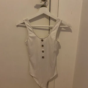 H&M vit body  - En vit body med bruna knappar