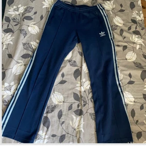 Adidas original retro trackpants - Mörkblå adidas original trackpants. Köpta secondhand och är i använt skick. Passar i längd på den som är ca 165-170. Ena blixtlåset på benet går inte att öppna då den blivit ihopsydd, men blixtlåset sitter alltså kvar och ser normalt ut.