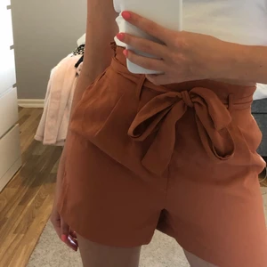 Brun/orangea kostymshorts - Säljer ett par snygga brun/orangea kostymshorts ifrån Gina Tricot, storlek 34 (XS), bra skick, sällan använda, ordinarie pris: 249kr mitt pris: 100kr (frakten ingår)