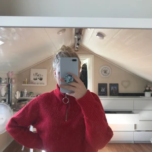 Stickad tröja - En röd stickad tröja som har dragkedja vid halen