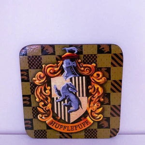 Harry Potter Mugg underlägg - Hufflepuff muggunderlägg, säljer då det inte används. Liten skada (se bild 3), köparen står för frakt som kostar 12kr. Andra bild för referens♥️ 