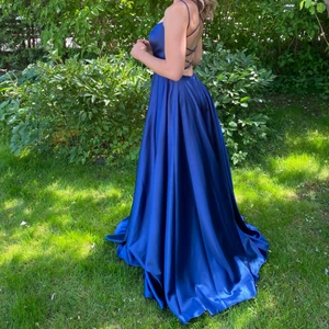 Blå balklänning i satin - Köpt från Forever Unique för 5000kr. Storlek 36 men mkt reglerbar på grund av banden i ryggen. Använd en gång, ej kemtvättad men inga fläckar vad jag kan se. Kan tänka mig att sänka priset vid snabb affär.