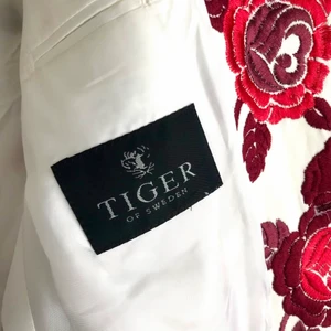 Unik Tigerkavaj anno 2003 *nyskick* - Ovanlig och gediget välsydd Tiger of Sweden kavaj med rosmönster, inköpt 2003 och endast använd vid två tillfällen. Absolut toppenskick. Material: 100% Ull. Lining: Viscose. Modell: Tobbe. Storlek: 46 (herr) men snarare 48 då generös passform.