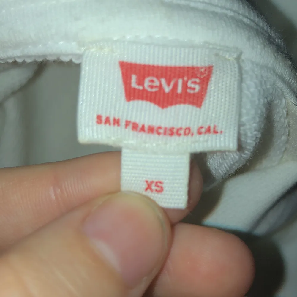 En vit croppad Levis hoodie med vändbara paljetter! Använd en enda gång och är i mycket fint skick! Hoodiens ordinarie pris är 650kr.  🤍🥥🦢. Hoodies.