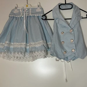 Kjol + väst - Kjol med hängslen och söt spets med matchande väst. Köpta på spreepicky. Små i storleken (korta), men rätt anpassbara tack vare stretch och snörning. Passar mig (170cm strl xxs-xs) men rekommenderar shorts under kjolen. Kan mötas upp i Sthlm. Köpare står för frakt. Tar endast swish.