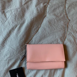 Nude/ljusrosa väska med kedjeband - Säljer denna oanvända väska från Prettylittlething. Ljusrosa/nude färg med silvrig kedja. Kan även användas som clutch. 