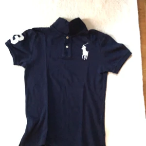 Ralph Lauren Piké Strl L/14-16 Mörkblå - En fin Ralph Lauren Piké i strl L/14-16 mörkblå. Använd endast ett par enstaka gånger vid särskilda tillfällen. Mycket gott skick, felfri! Nypris: 1000kr