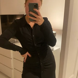 Klänning med knappar - Klänning med knappar hela vägen samt rynkning vid magen. Snygg krage och är figurnära