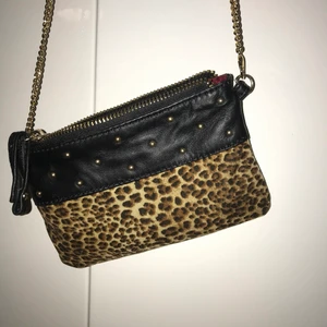 Liten väska i skin/leopardmönster - Säljer nu denhär lilla väskan i leopardmönster/ med gulddetaljer. Den är väldigt liten så i den är ungefär lika lång som en mobil, dvs mobilen får plats. Kedjan är längre så den kan man ha över bröstet. Köpt av ett danskt företag men minns inte vad det hette!