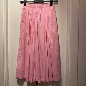 Superfin ljusrosa kjol med fickor från Gina Tricot i midimodel. Storlek XS. Endast använd en gång 