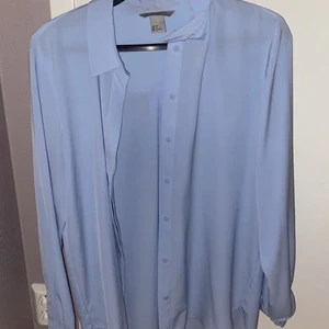 Blå Blus - Använd ett par gånger. När man knäppt knapparna syns de inte så de blir täcka av tyget. 