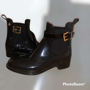 Boots - Svarta glansiga regn boots med guld detaljer som är supersnygga och eleganta!! Enkelt att sätta på och dra av. Använd en gång endast, så den är i nyskick. Storlek 36