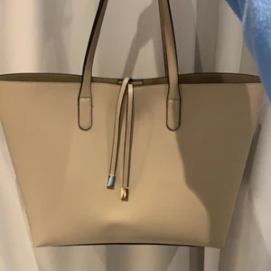 Fin handväska! - En stor och rymlig handväska från Glitter. Veskan är beige med guld detaljer. OBS! Priset inkluderar inte frakten.