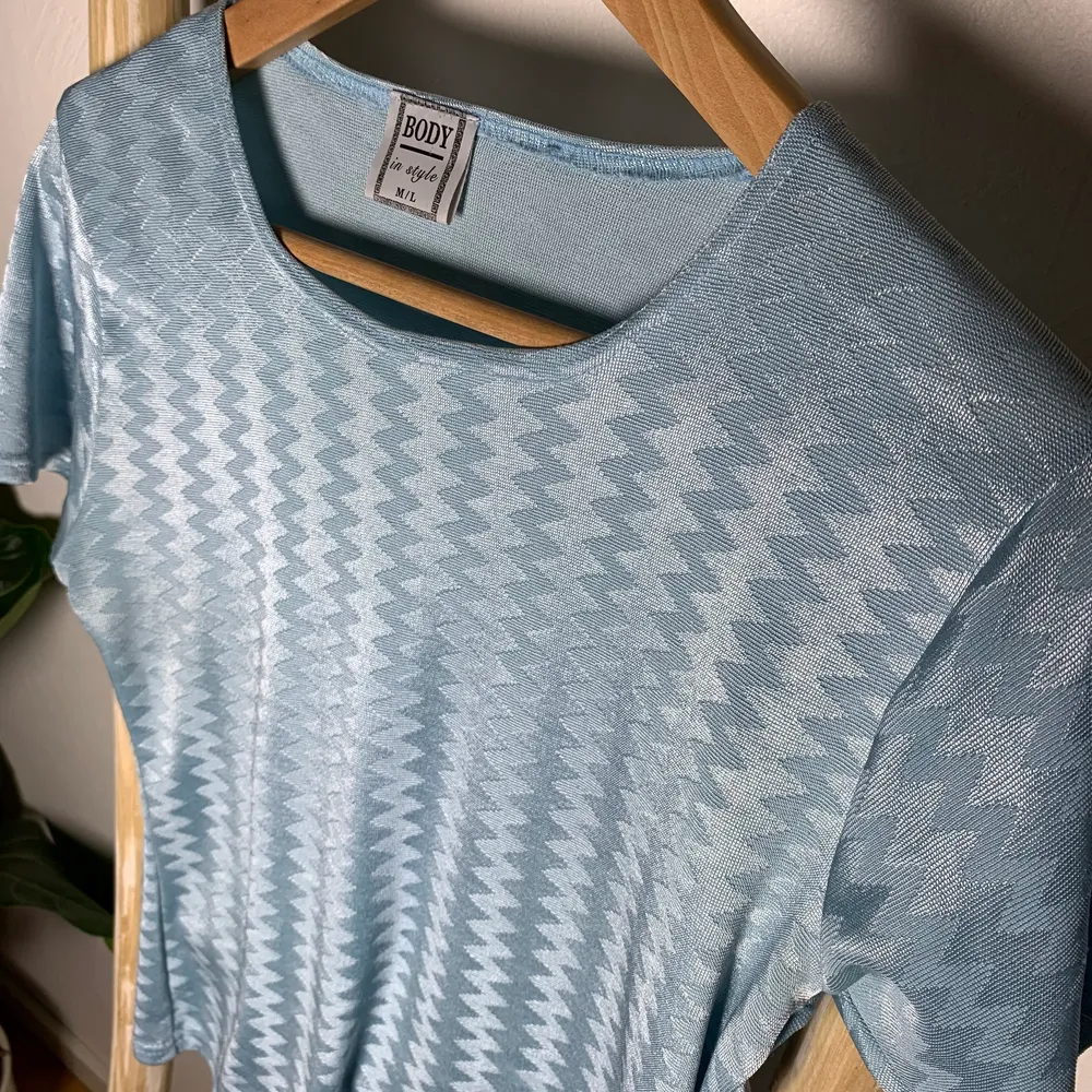 En blå tshirt som har ett glansigt, mönstrat material. Den är stretchig och knappt använd. Så fin på sommaren! Passar XS-L.. T-shirts.