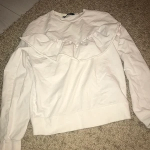 Tröja med volanger på - En vit långärmad tröja med volanger på i storlek xs ifrån bikbok. Köparen står för frakten!
