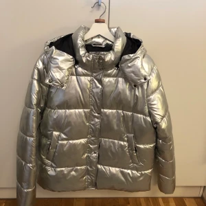 Ny silver jacka i storlek M -  •Luvan går att ta av. Jackan var aldrig använd.  •Normal i storleken. Mycket fin och trendig •Pris: 250 kr •Finns på fler sidor. Först till kvarn. 🚫Djurfritt och rökfritt hem 📍Kan mötes upp i Mölnlycke 📬Kan skickas mot fraktkostnad (66 kr)