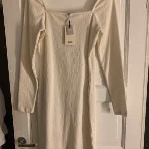 Krämvit klänning - Aldrig använd. Klänning med fin passform i ett räfflat tyg.