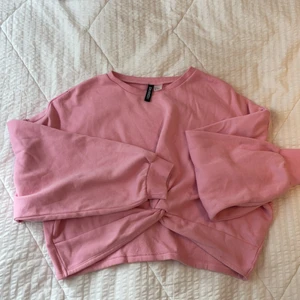 Rosa kroppar oversized tröja  - Rosa tröja från H&M! Oversized croppad med gullig knytdetalj fram! Strl XL divided - skulle vilja säga mer M/L