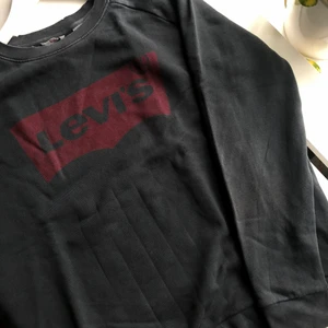 LEVIS SWEATSHIRT MED SLITNA DETALJER  - En svart/grå/blå sweatshirt från Levi’s med slita detaljer vid muddarna. Sparsamt använd så fint skick! Kan mötas upp i Göteborg, annars står köparen för frakten💙