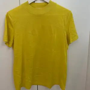 Säljer denna gula t-shirt i silkesbladning från H&M. Den är använd ett fåtal ggr och är i mkt fint skick. Priset är exklusive frakt