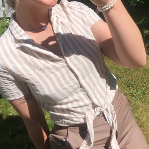 Knytblus  - Randig beige-vit knytblus från Vila köpt förra året. I storlek 36. Knappt använd pga för liten runt bysten. Frakt ingår!  🤍