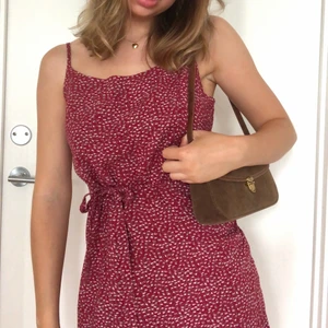 Brandy Melville klänning  - Brandy Meville klänning i röd blommigt tyg 🌻 Mjukt och tunnare skönt tyg som passar till sommaren ☀️ Har ett band så man kan göra en knytning antigen fram eller bak 💕säg till om ni vill ha mått! Tex längd etc. 🌼 Aldrig använd! Står ej storlek men passar XS-S