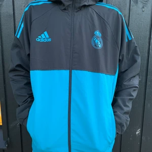 Real Madrids vindjacka i storlek L - Adidas kofta som är real Madrids tränings vindjacka. Riktigt skönt när man tränar fotboll och det blåser lite. Köpt från adidas för 700kr men jag säljer den för 300kr