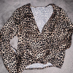 Leopard Blus - En leopard blus/skjorta i storlek 36 ifrån NA-KD. Använd 1 gång och därav i bra skick. Materialt är som silke med ett resårband runt midjan och uppknäppbar vid brösten och i armarna. 