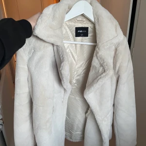 Pälsjacka beige  - Ljus beige pälsjacka använd en gång. Den är i helt ny skick köpt för 2 månader sen. Storlek S men passar upp till L