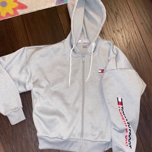 Ny Tommy Hilfiger hoddie med dragkedja! - Mycket fin hoddie i märket Tommy Hilfiger! Har aldrig kommit till användning och därav jättefint skick, som ny!! Nypris 1050kr  Storlek xs men kan passa s också beroende på hur man vill att den ska sitta!  