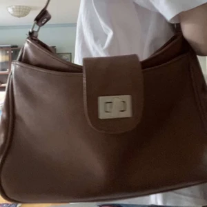 Brun väska - Säljer min bruna väska som är köpt secondhand💕jättefint skick och felfri. Den är praktisk så det finns ett ytter fack och dessutom innerfack. Knäpps med dragkedja och en knapp som syns på bilden