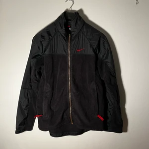 Nike Fleece svart/röd Small - Bra använt skick, inga defekter jag märker. Några knottror lite här och där, ganska få dock. Kedja verkar ej vara original. Fler bilder och mer info kan skickas vid förfrågan.