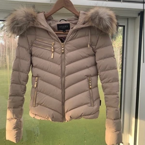 beige Hollies jacka! - säljer nu min fina Hollies jacka i storlek 34, skicket är ganska bra den är sparsamt använd, inga hål eller ngt men den är lite smutsig men det är bara att tvätta den. annars är den super fin! pälsen är äkta❤️ kontakta för fler bilder! (lånad bild) pris kan alltid diskuteras☺️