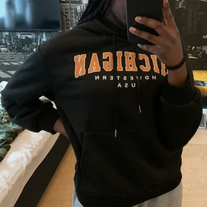 Svart hoodie - En fin och skön svart hoodie med orange och vit text. Materialet är fint och skönt med en mjuk insida. Den är helt oanvänd. Skriv vid intresse, frakt tillkommer:)