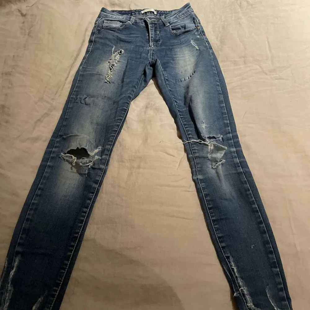 Ett par blåa jeans med hål i i storlek 34. Nypriset ligger på 200kr men säljer för 120kr dom har lite defekter på sig men inget man tänker på.. Jeans & Byxor.