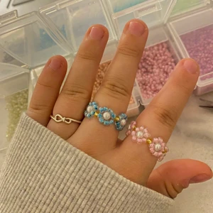 Super söta ringar - Säljer en variant av de trendiga blomringarna som är super gulliga. De har en vit runf pärla i mitten istället för en vanlig pärla. Så sjukt gulliga och perfekt till sommaren . 🤍 De guldiga pärlorna mellan blommorna behöver inte vara med. Man kan designa ringarna hur som helst, mönster, färger och antal blommor. ⚡️ Pris beror på design.