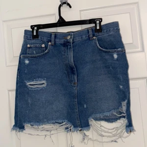 Jeans kjol - En jeans kjol från NAKD med slitningar. Kort modell. Skulle säga att detta är en M och inte L.