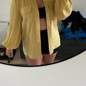 Gul skjorta - Gul skjorta med puffiga ärmar och i silkesliknande material, superfin att ha till ett par jeans eller över en bikini tex. Aldrig använd, lappen sitter fortfarande kvar! Du står för frakt!