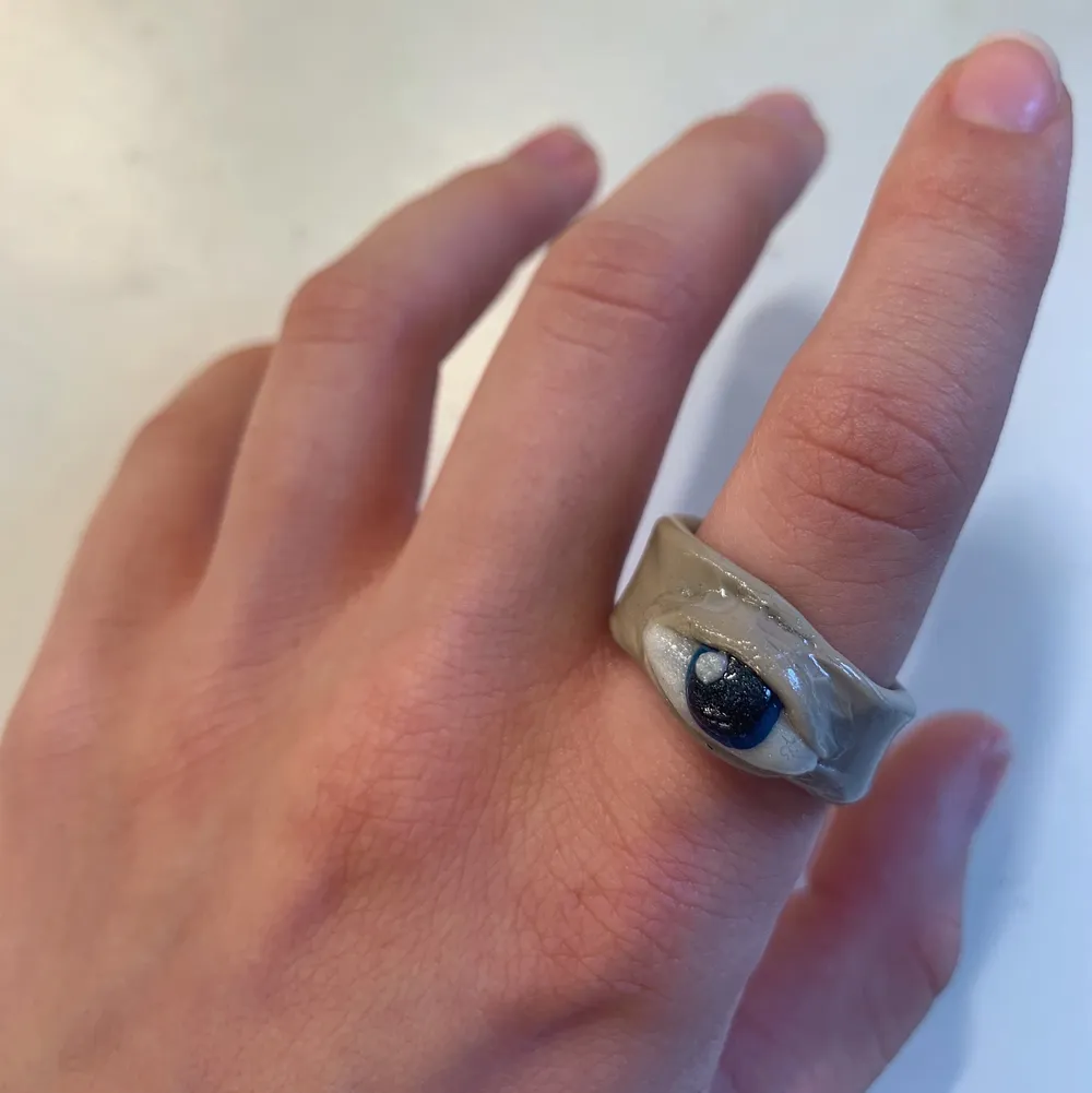 En beige ring med ett blått öga, gjord i lera👁✨. Accessoarer.