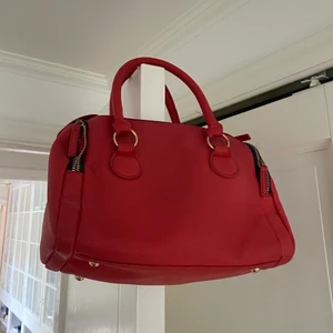 Röd handväska  - Röd väska i fakeläder, finns långt band på också.