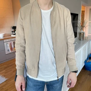 Beige vårjacka Jack & Jones HERR - Herr vårjacka från Jack & Jones. Strl M. Använt skick. Ett par små hål från en cigg, lite nopprig. Innerficka. 
