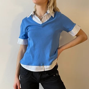 Two in one t-shirt skjorta - Jättetjusig topp i den bästa blå färgen. Skjortan är inbyggd i t-shirten. Beroende på hur man vill ha passformen funkar toppen även här S/M