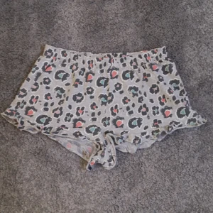 Grå pyjamas shorts med leopard mönster - Grå pyjamas shorts med leopard mönster i färgerna blå, orange och rosa. Storlek: 170. Stretchiga och resor i midjan 