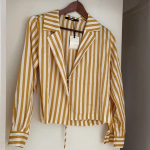 Gul och vitrandig blus  - Aldrig använd pga för liten för mig. Knytband för att markera midjan medföljer. 