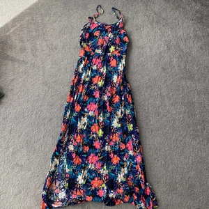 Blommig långklänning stl 34 - Härlig långklänning med blommigt mönster och långa slitsar på båda sidor. Aldrig använd, som ny. Stl 34. Djur- och rökfritt hem.