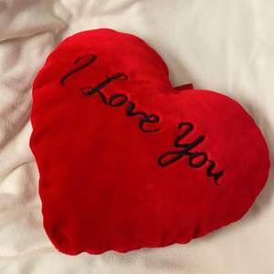 En röd kudde som är format som ett hjärta. På den står det I love you.                                                                              Frakt tillkommer!