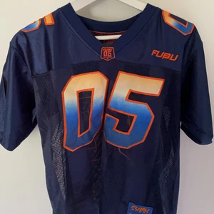 Fubu tshirt - 90/00 talets stora hip hop märke Fubu och deras sportiga mesh tisha. Knappt använd och förvarat bra. Strl S men är mer XS till kille och funkar som S till tjej.