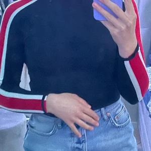 Blå/röd/vit tröja - Tajt tröja med röd och vita ränder. Själva tröjan är marinblå. Långärmad. Frakten tillkommer