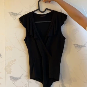 Bodysuit  - Svart v-ringad body med volanger från Vero Moda. Säljes pga att den ej används längre. Stl 34.🌼